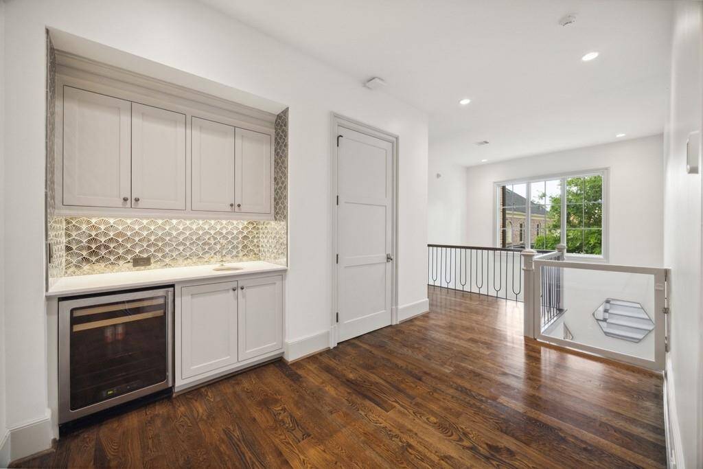 Located just off the upstairs game room, this bright landing features a built-in wet bar with custom cabinetry, beverage fridge, and eye-catching tile backsplash—ideal for entertaining. The adjacent closet is elevator-ready, offering future convenience without compromising style.