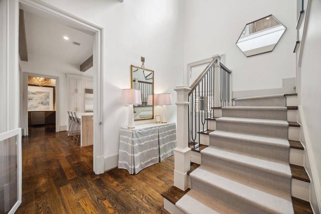 Stylish back staircase with hardwood treads, iron railing, and natural light—conveniently located off the kitchen with direct access to the driveway.
