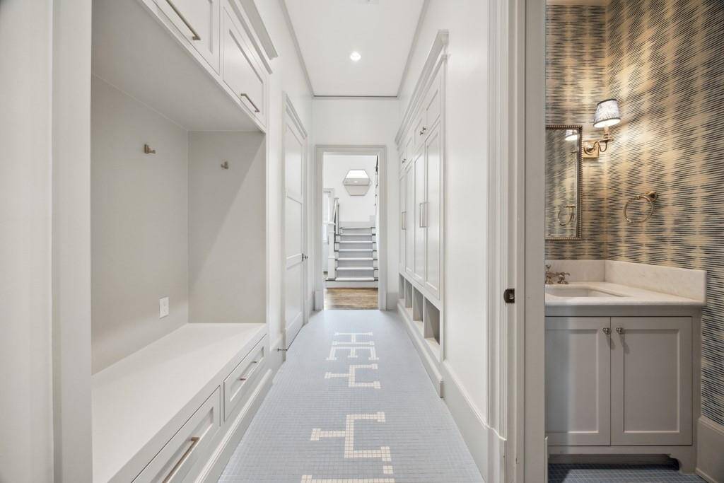 Custom mudroom with built-ins, playful tile, and a nearby half bath—conveniently located off the back stairs with access to the backyard and pool.