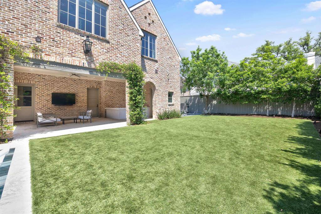 Beyond the pool, an expansive turf yard offers space for play, framed by lush greenery for added privacy. The covered outdoor living area is ideal for year-round entertaining. A whole-house generator is discreetly tucked behind the home for peace of mind.