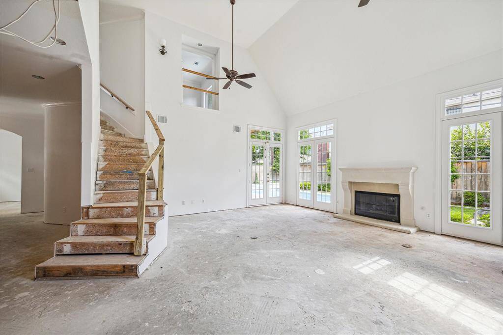 Spacious living room with soaring ceilings, abundant natural light, and a beautiful stone fireplace—ready to be transformed into a cozy yet elegant gathering space.