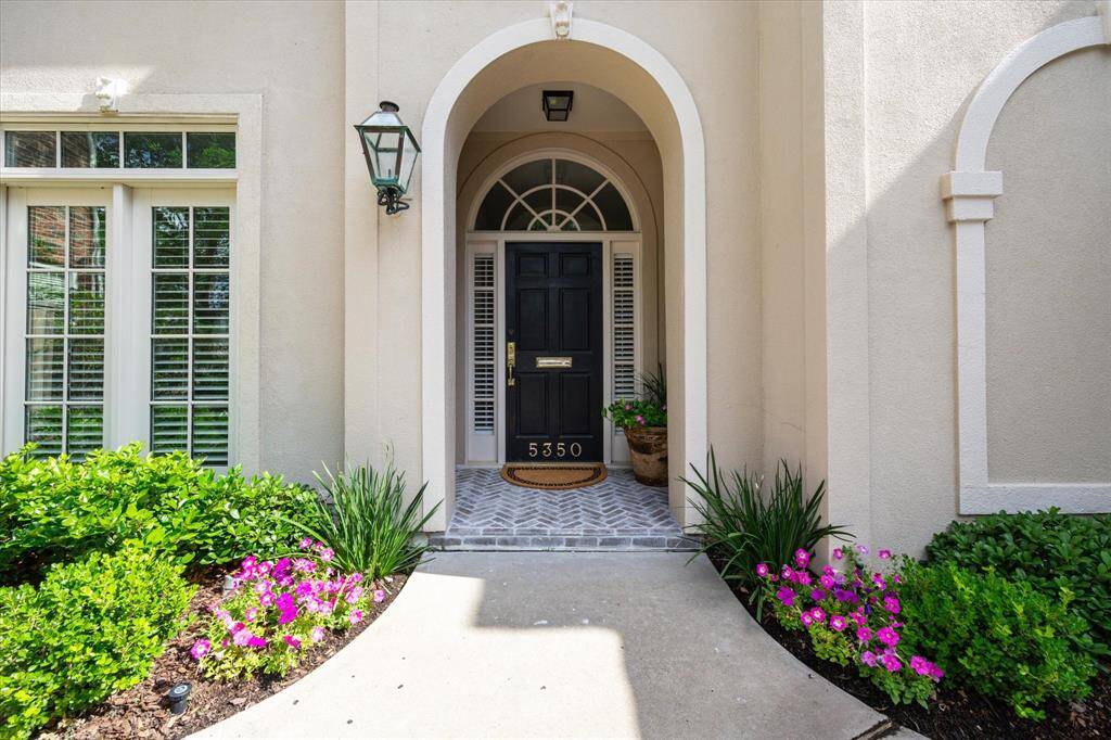This elegant French-inspired exterior boasts charming architectural details, a two-car garage, and a graceful arched entry.