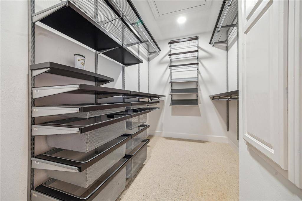 One of two expansive primary closets, each featuring a customizable storage system with pull-out mesh drawers, shelving, and hanging space—designed to keep your wardrobe beautifully organized.