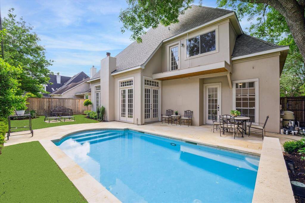 French doors open to a resort-style outdoor space, complete with lounge areas and a picture-perfect pool.