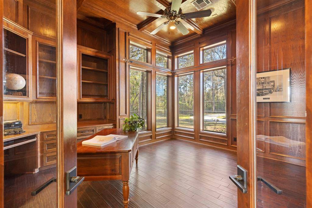 The study, where elegance meets functionality. The rich wood paneling and expansive windows invite an abundance of natural light, creating an ideal workspace. With ample built-in storage and a serene view.