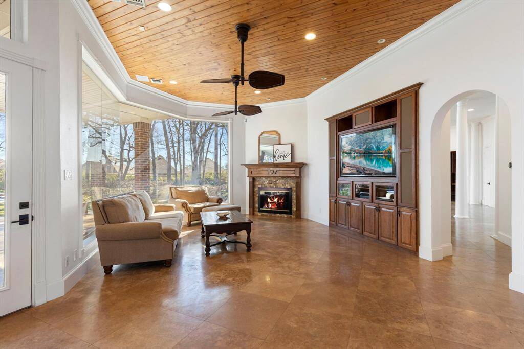 The warmth of this enchanting living space, where rich wood ceiling details and a cozy fireplace invite comfort and connection. Oversized windows frame serene views, creating a seamless blend of indoor and outdoor living.