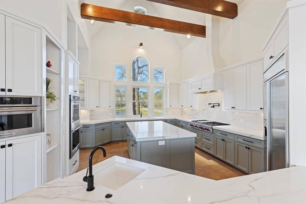 Quartz countertops sparkle with each ray of sunlight cascading through grand arched windows. Recently renovated, this gourmet kitchen boasts professional-grade appliances and a tasteful fusion of modernity and classic charm, crowned by elegant beams. Here, every meal becomes a gourmet adventure waiting to be savored.