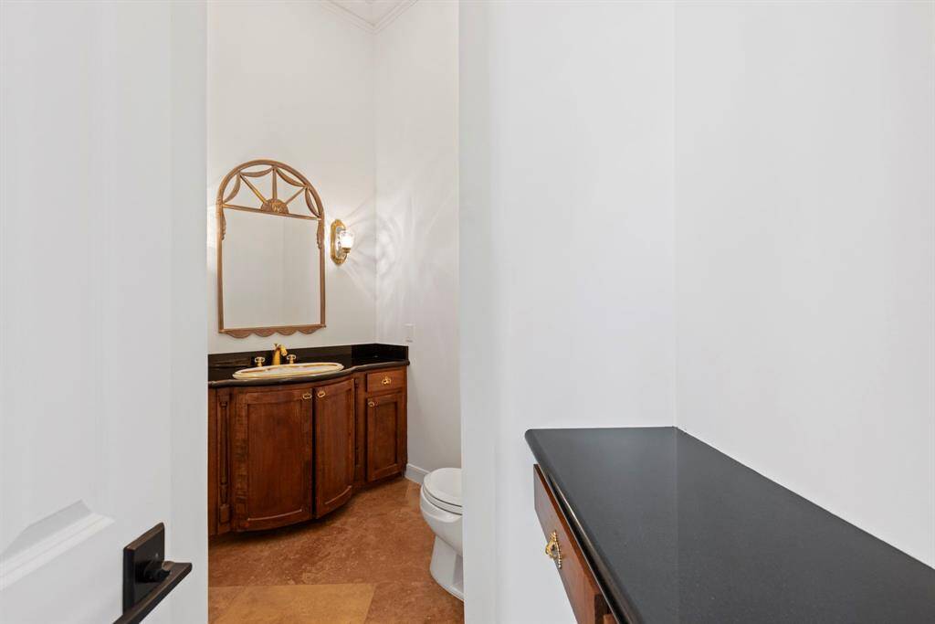 This tastefully appointed first floor powder room, where rich wooden cabinetry and sleek countertops harmonize to create a sanctuary of style for daily life or guest alike.