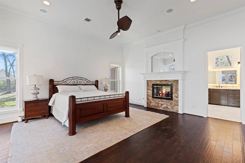 The primary suite dazzles with its exquisite hardwood floors, a charming fireplace, and serene views through expansive windows.