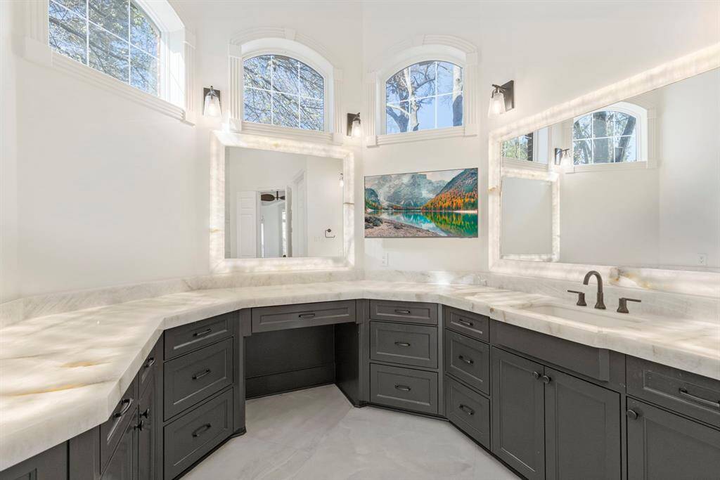 With dual vanities and illuminated mirrors cast a gentle glow on exquisite countertops. With custom cabinetry providing a symphony of style and functionality, this sanctuary beckons relaxation. An enclave of serenity, perfect for pondering life’s great mysteries—or just marveling at remarkable craftsmanship.