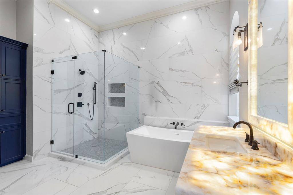 The second primary ensuite bathroom boasts exquisite floor to ceiling tile, invoking the essence of a modern spa. The frameless glass shower and luxurious soaking tub invite relaxation, while the vanity with its luminous countertop ensures every day begins and ends in timeless style.