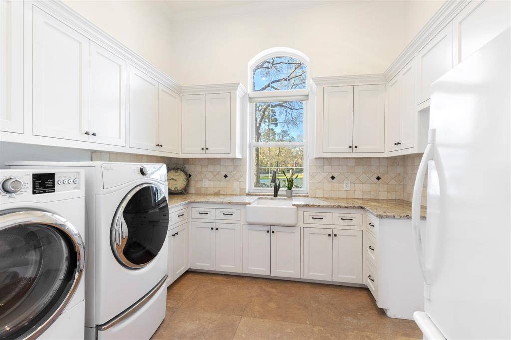 Welcome to the laundry room that redefines multitasking supremacy! With pristine white cabinetry, a charming farmhouse sink, and an elegant view outside, mundane chores transform into delightful rituals.