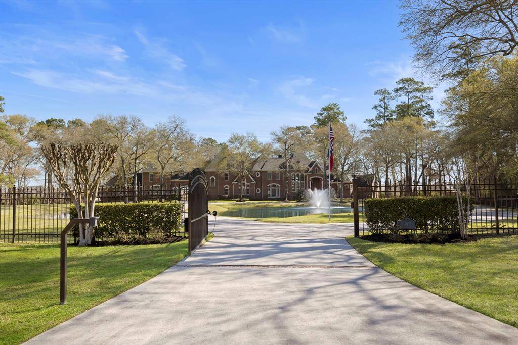 Welcome to a sanctuary where elegance meets privacy. As the gates part, a grand driveway leads you past a serene pond with a cascading fountain, setting the stage for the opulent estate beyond.