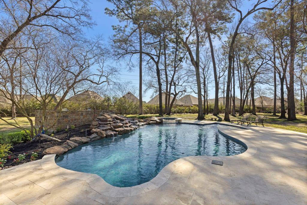 Escape to your own private paradise with this serene outdoor oasis, featuring a meticulously designed heated pool framed by lush landscaping and tranquil wooded surroundings. Dive into relaxation or lounge by the cascading waterfall as gentle breezes whisper through the trees. Ideal for both grand gatherings and quiet reflection.