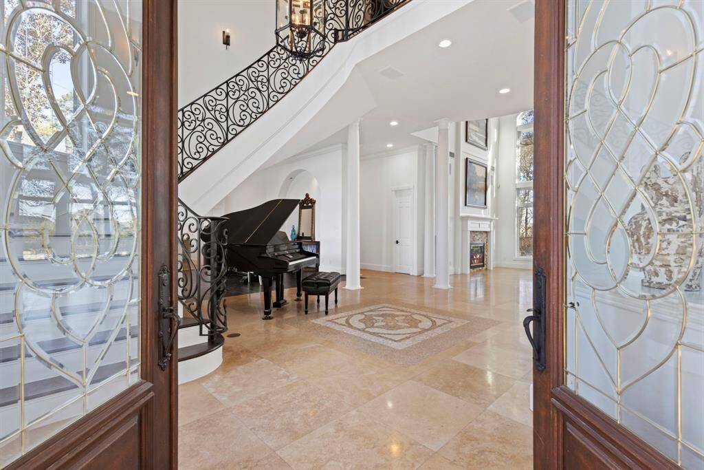 Step into elegance through these exquisite double doors to find a grand entry, graced by a recently upgraded wrought iron staircase. The polished travertine floors and open, light-filled space that whisper luxury.