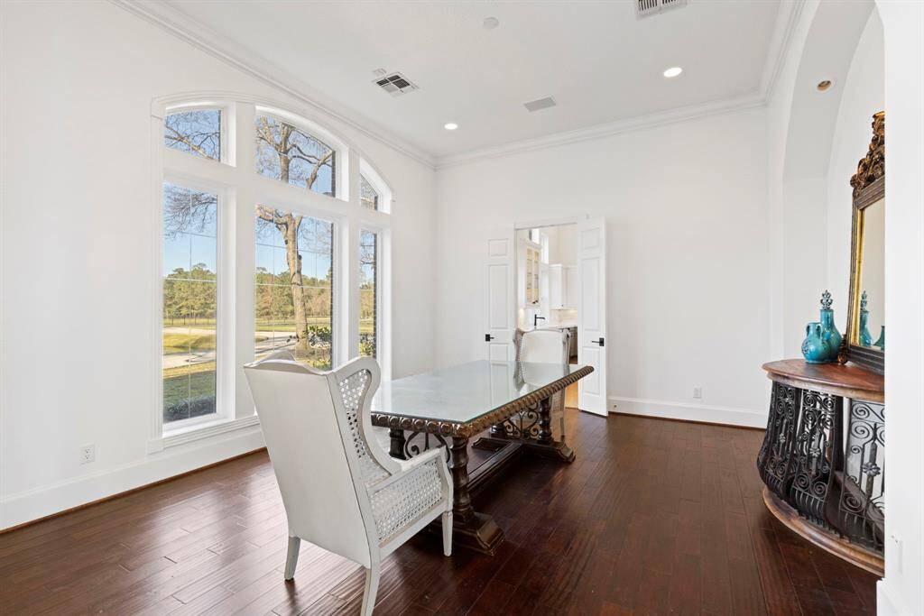 Bask in the warmth of natural light streaming through grand arched windows, illuminating the elegant dining space with rich hardwood floors.