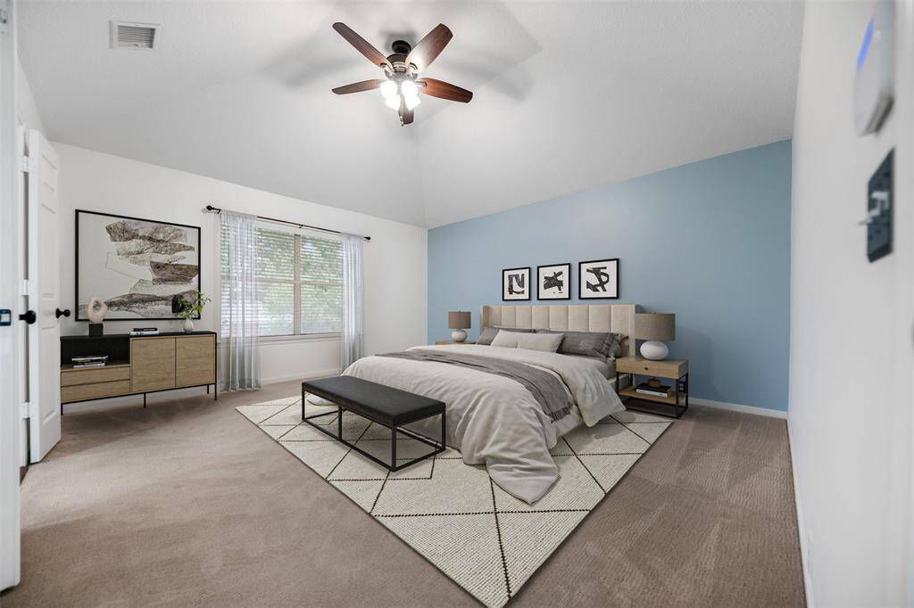The primary bedroom is spacious and serene, featuring a large window that fills the room with natural light. A ceiling fan adds both comfort and style, while the adjacent ensuite bath provides a private retreat, enhancing the room's relaxing ambiance. (This photo is virtually staged)
