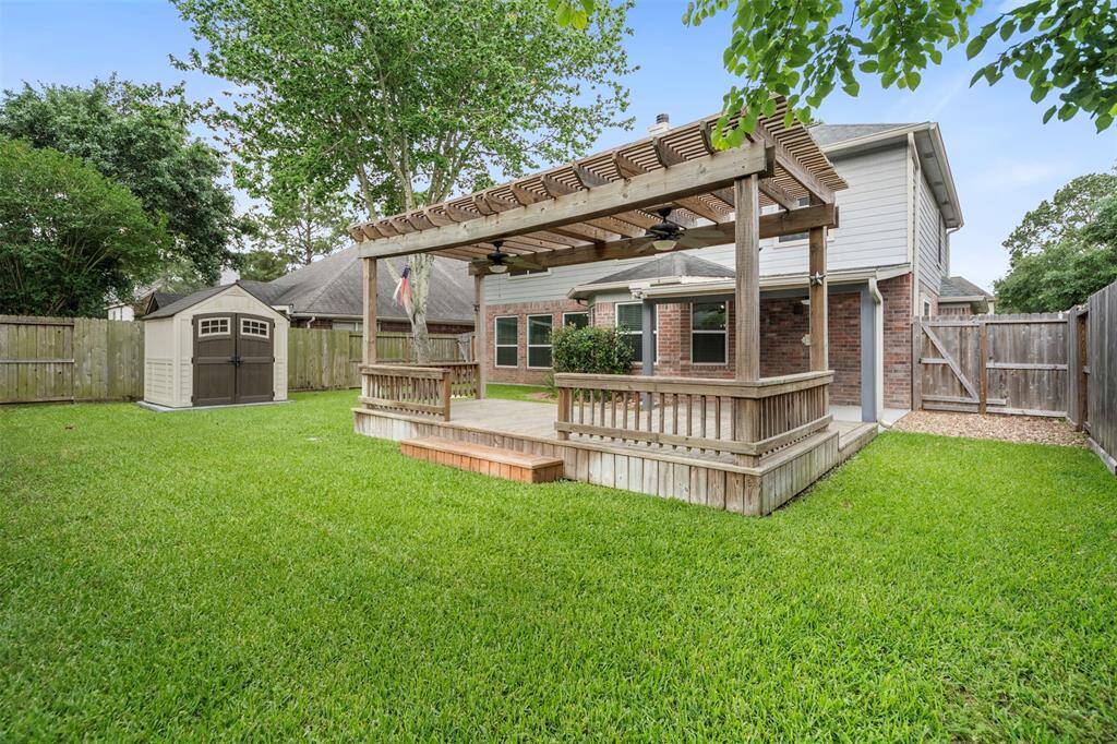 The backyard is fully fenced, offering privacy and security, making it a perfect space for outdoor activities. A convenient storage shed is tucked neatly at the corner, providing additional space for tools or equipment, while the expansive yard offers plenty of room for play or relaxation.