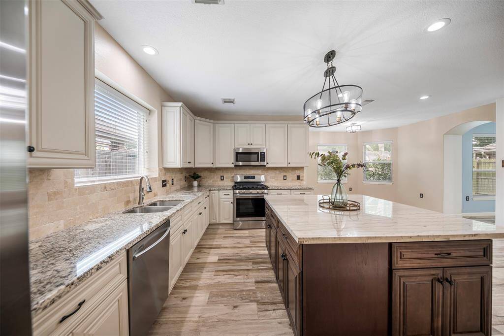 The kitchen island is impressively large, offering abundant space for meal prep, entertaining, or casual dining. The surrounding countertops provide ample room for all your kitchen needs, creating an efficient and spacious layout. A conveniently placed dishwasher adds to the functionality, making clean-up a breeze while maintaining the sleek, modern design of the space.