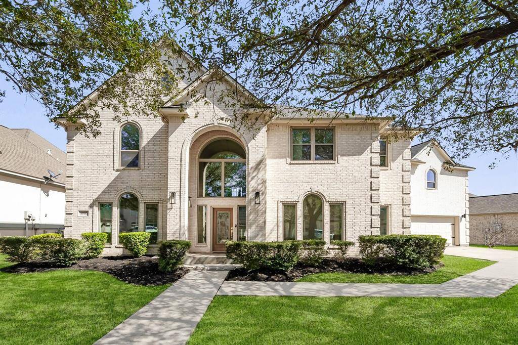 The symmetrical design of this stunning brick home is framed by manicured hedges and mature shade trees. A long driveway and welcoming walkway guide you to the impressive front door beneath a soaring arched entry.