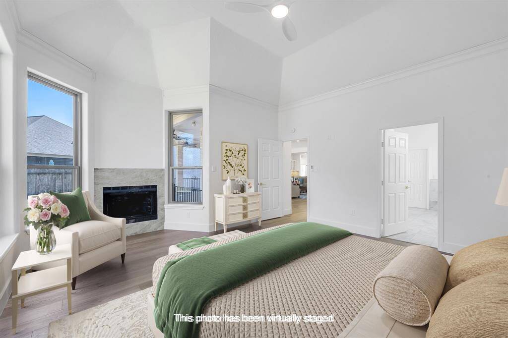 Virtually staged to show its full potential, this serene primary suite features tall ceilings, large windows, and a cozy corner fireplace. There’s plenty of room for a king-size bed and sitting area.