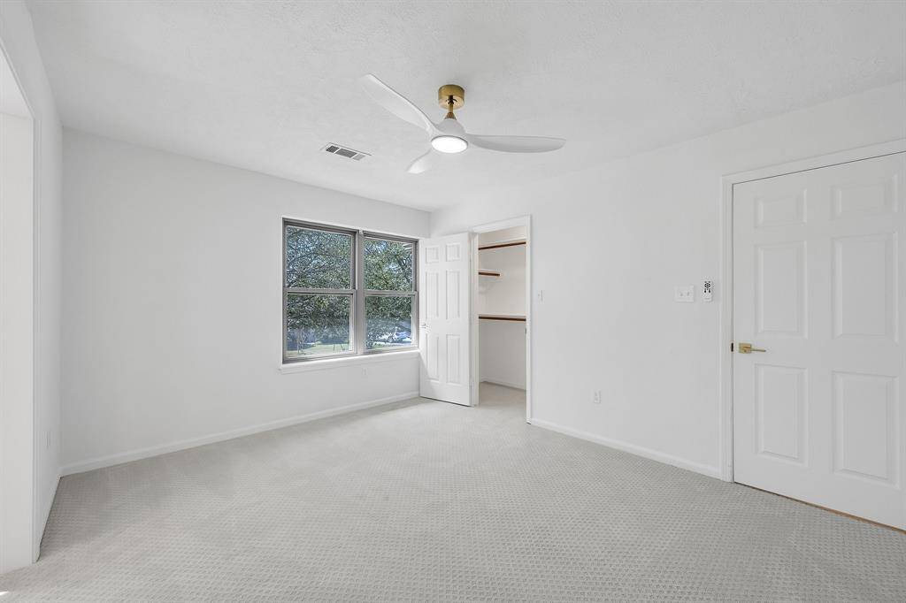 This reverse view shows the generously sized bedroom with walk-in closet and bright windows that fill the space with natural light.
