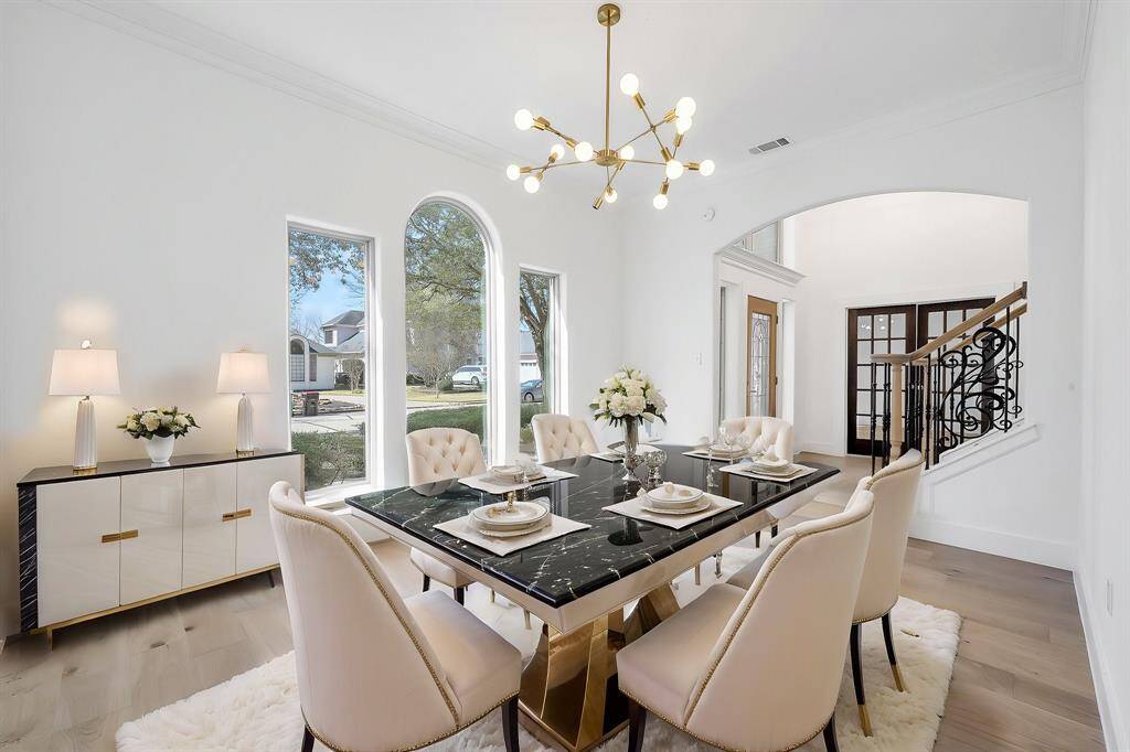 This luminous dining space boasts triple arched windows, elegant crown molding, and a statement gold chandelier. The neutral palette and contemporary accents create a perfect blend of sophistication and warmth.