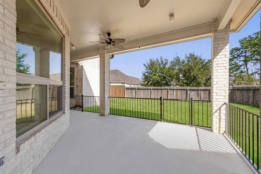 Enjoy outdoor relaxation on the large covered patio, featuring dual ceiling fans, recessed lighting, and iron railings.