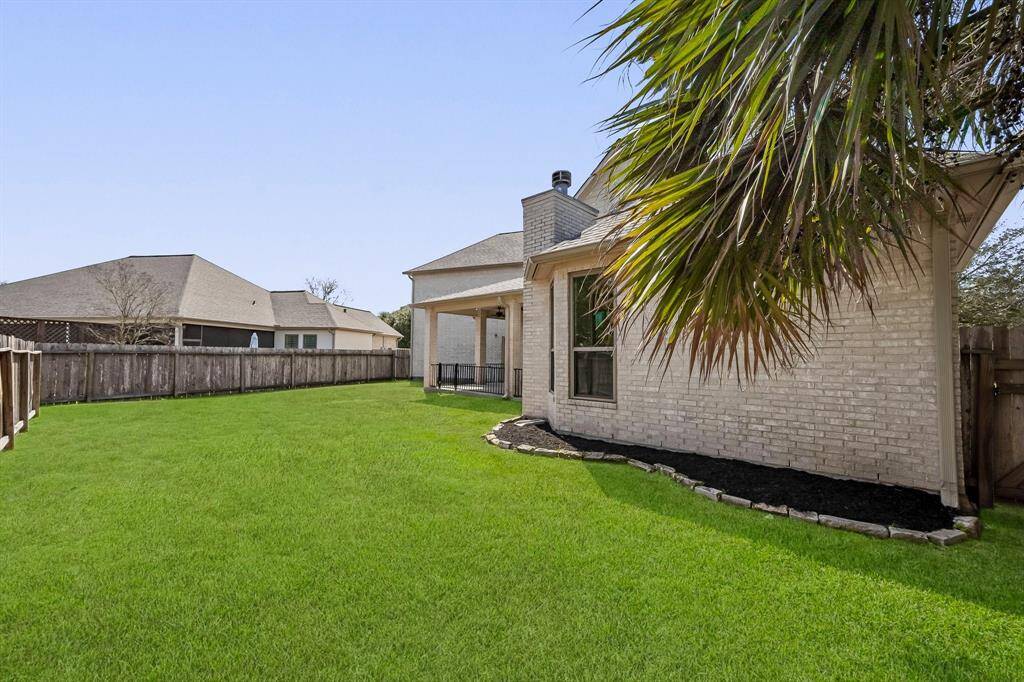 Spacious fenced backyard with low-maintenance landscaping and established trees for added privacy and curb appeal.