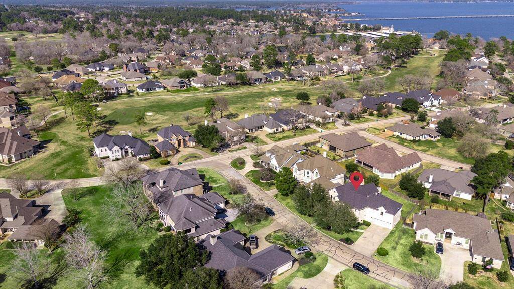 Zoomed-out aerial image showing the home’s ideal location in a serene, golf-course-adjacent community with water views and easy access to scenic green spaces.