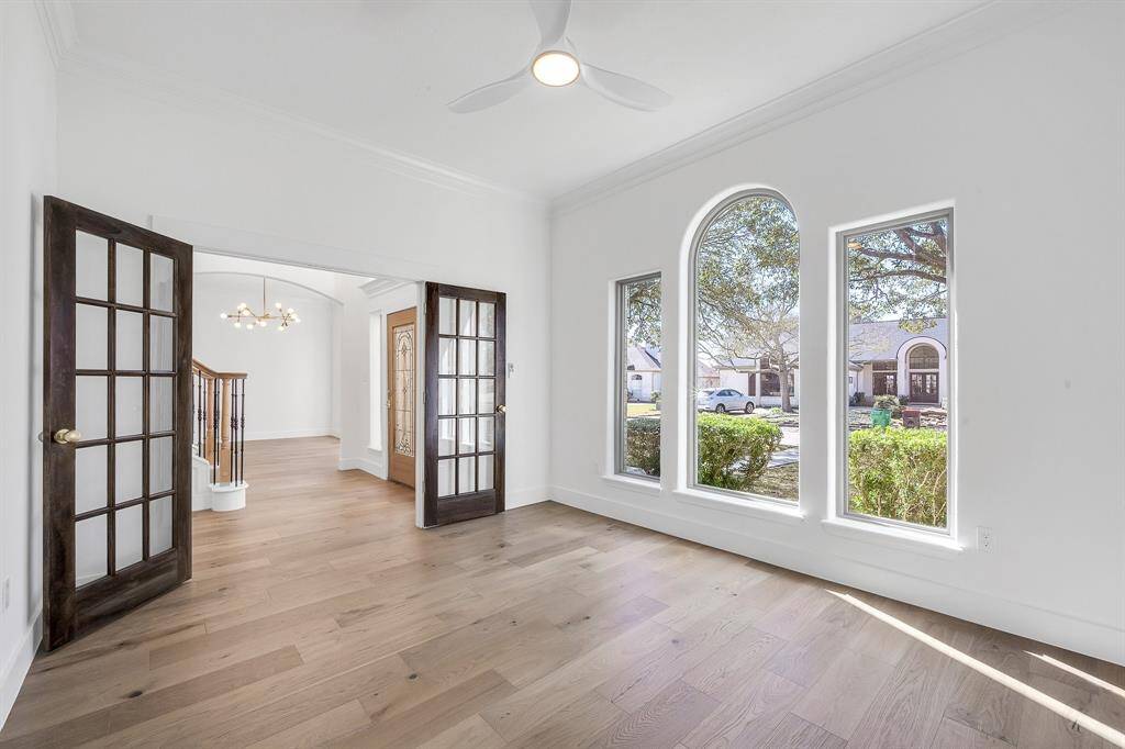 A versatile front room with French doors and expansive arched windows, ideal for a home office or reading lounge. The clean lines and open layout invite productivity and comfort.