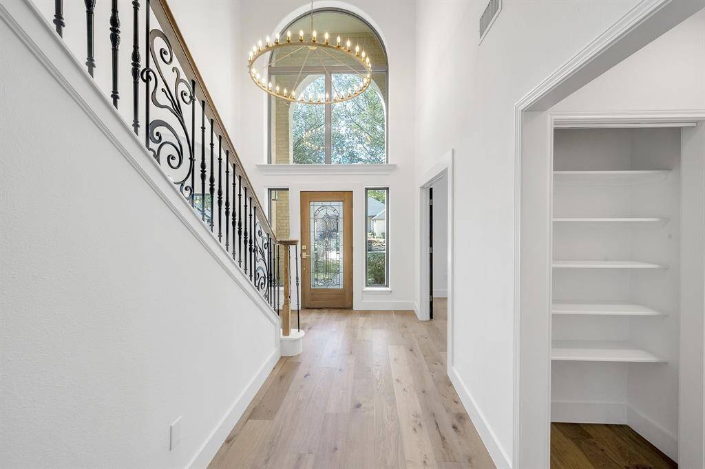 Make a memorable first impression with this breathtaking entry featuring a sweeping staircase with iron spindles, soaring ceilings, and a dramatic chandelier.