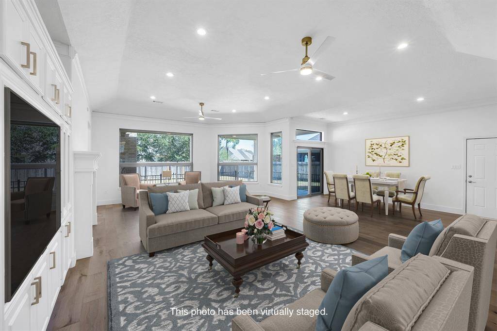 This inviting living room is designed for gathering and relaxing, with a cozy fireplace and built-in media cabinetry. Natural light pours in from every angle.