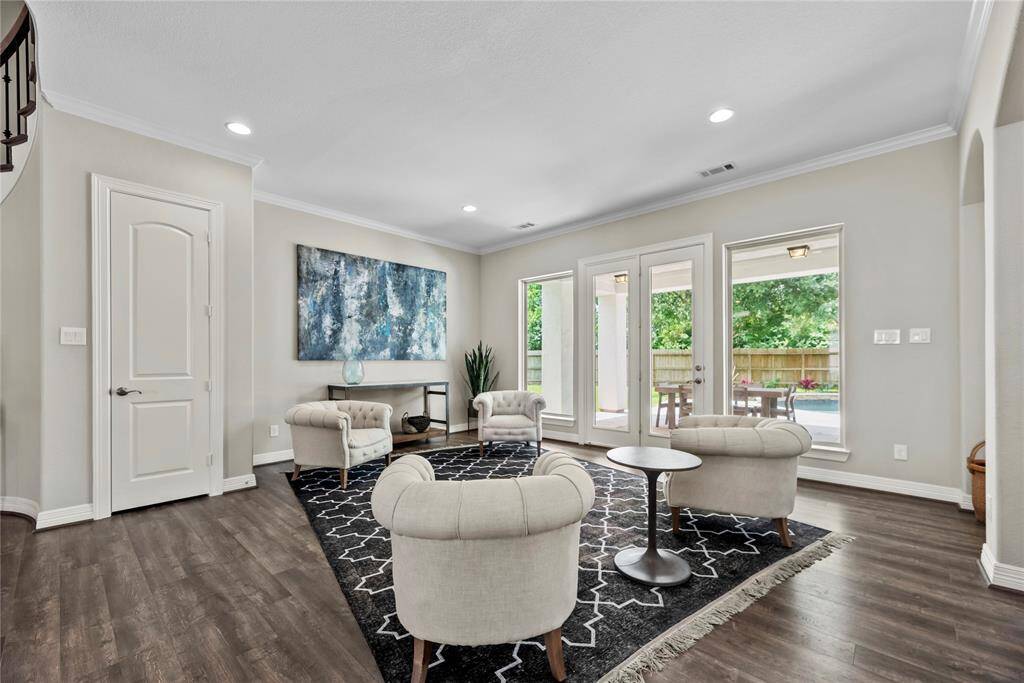 This elegant formal sitting room features refined finishes and a serene atmosphere, perfect for entertaining or quiet relaxation. Large windows frame picturesque views of the lush oasis backyard, blending indoor sophistication with outdoor tranquility.