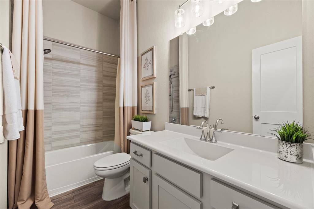 Full guest bathroom with a large vanity and tub/shower combination.