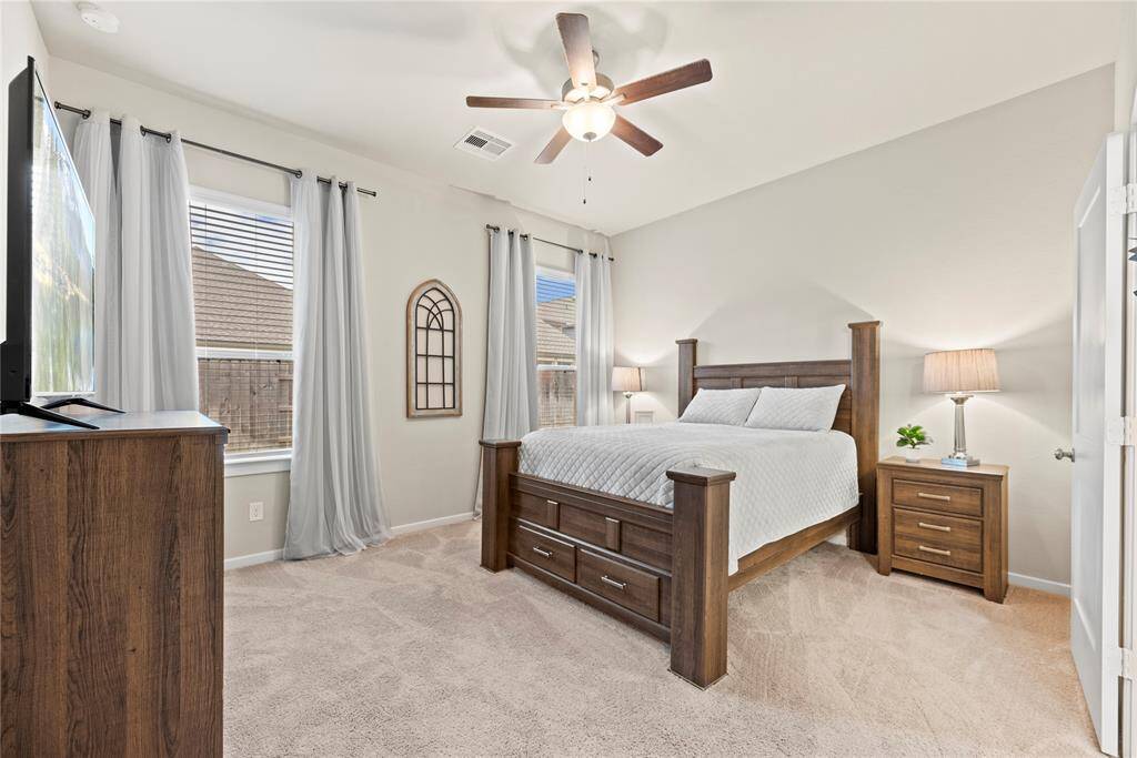 Primary retreat with a ceiling fan, plush carpet and an en-suite bathroom.
