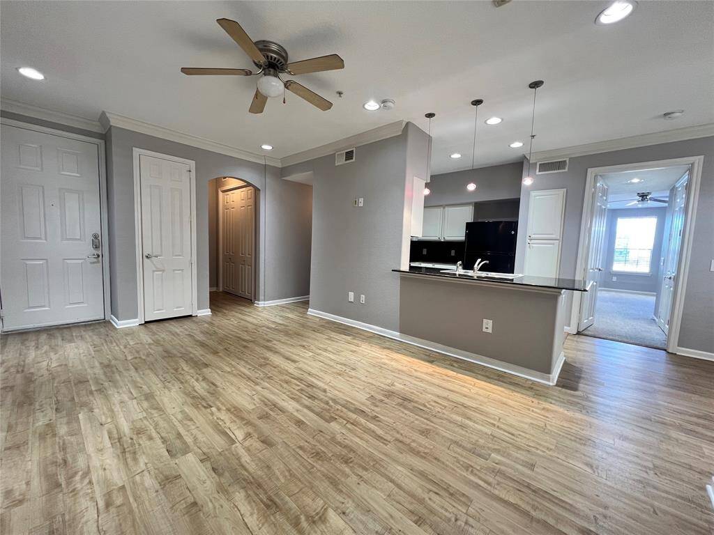 This view shows the large living area and kitchen. The primary bedroom is to the right of the kitchen. The secondary bedroom is to the left of the kitchen down the hall.