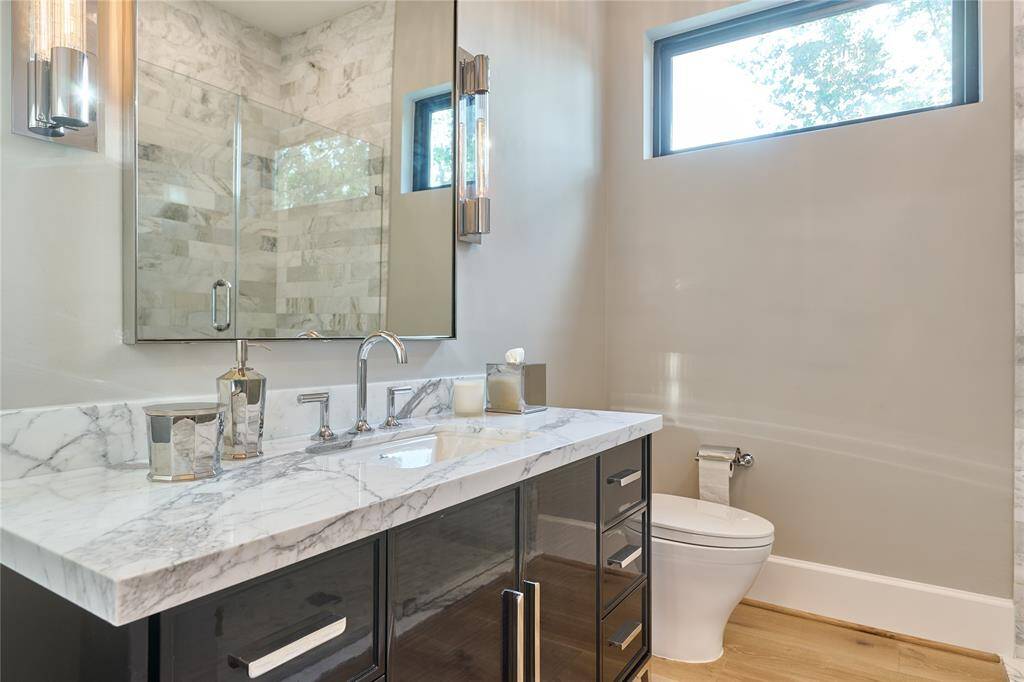 Elegant downstairs full bathroom featuring an antique vanity and a luxurious walk-in shower with stunning marble tile.