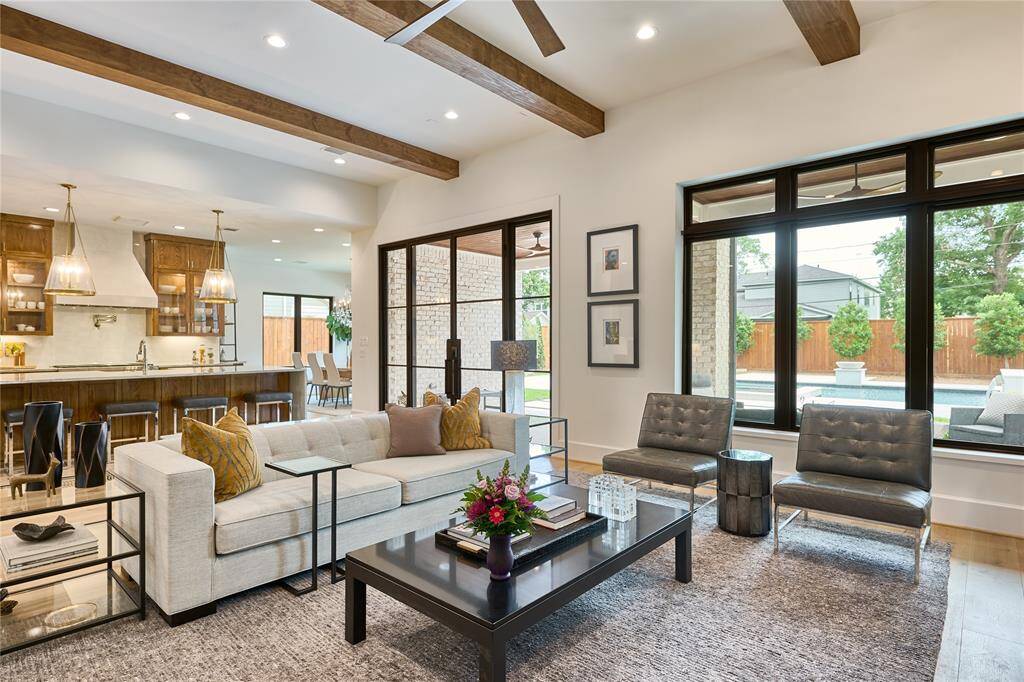 Bright living room lined with expansive windows, offering serene views of the back patio and pool, creating a seamless connection to outdoor living.