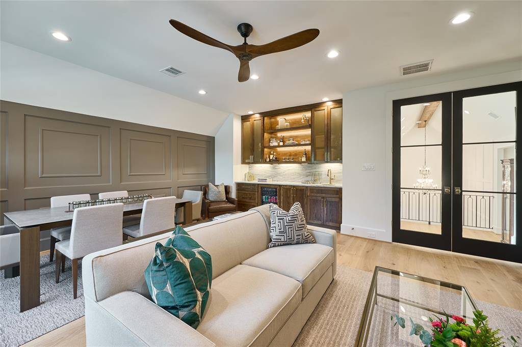 Inviting second-floor game room featuring a striking accent wall, elegant glass French doors, and a convenient wet bar—ideal for entertaining or relaxing.