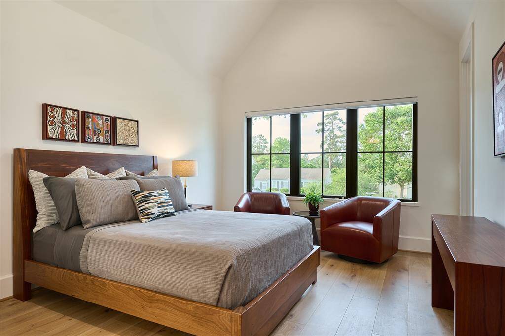 Charming upstairs secondary bedroom featuring large windows and soaring cathedral ceilings, creating an open and airy atmosphere.
