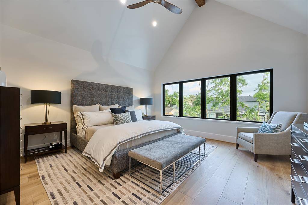 Expansive primary suite featuring tall cathedral ceilings and large windows that frame serene views of the backyard, creating a tranquil retreat.