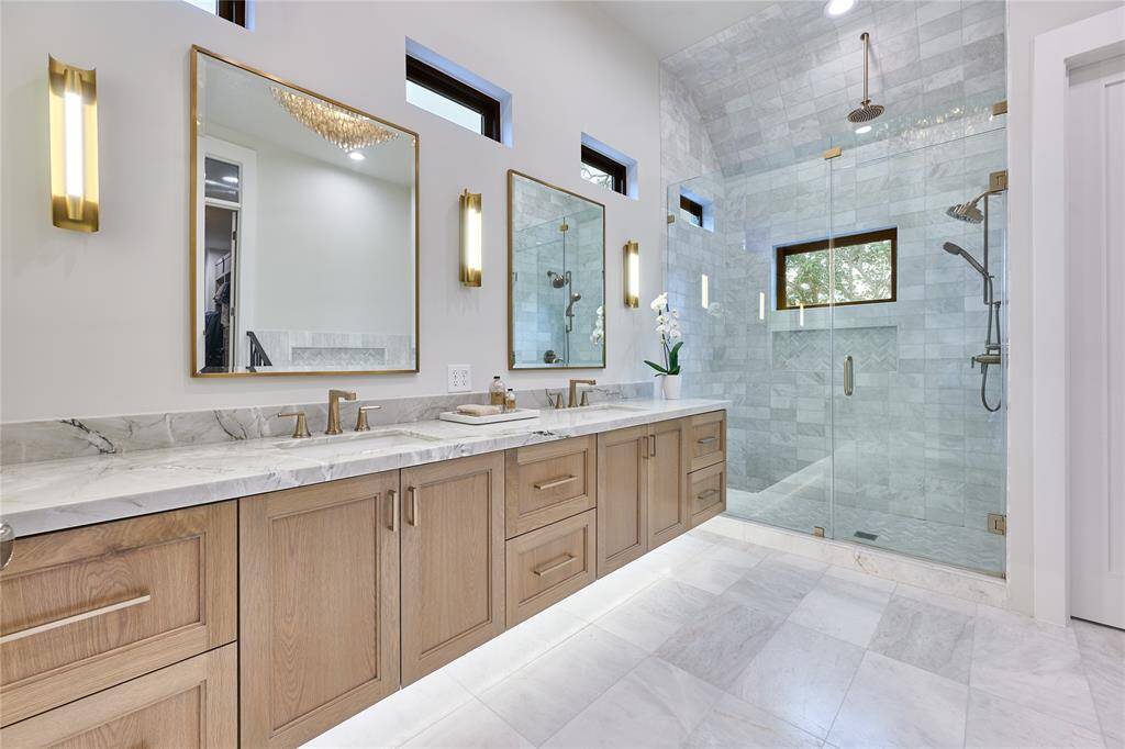 Luxurious primary bathroom featuring a walk-in shower adorned with stunning floor-to-ceiling marble tile, creating a spa-like atmosphere.