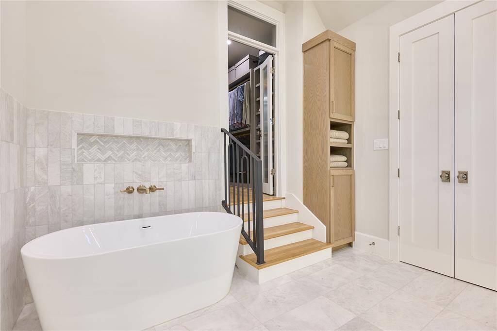 Relaxing soaking tub in the primary bathroom, with steps leading into the spacious walk-in closet, offering both luxury and convenience.