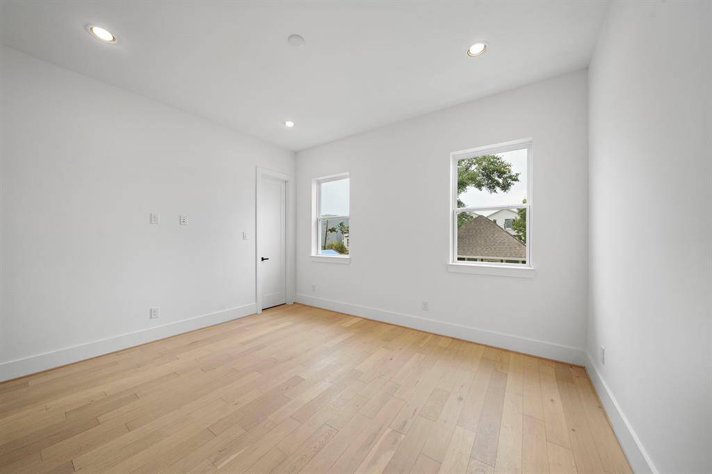 Photo of one of the sizable guest bedrooms with large closet and adjoining bath. (Photo is of a previously completed home that featured upgraded wood flooring.)