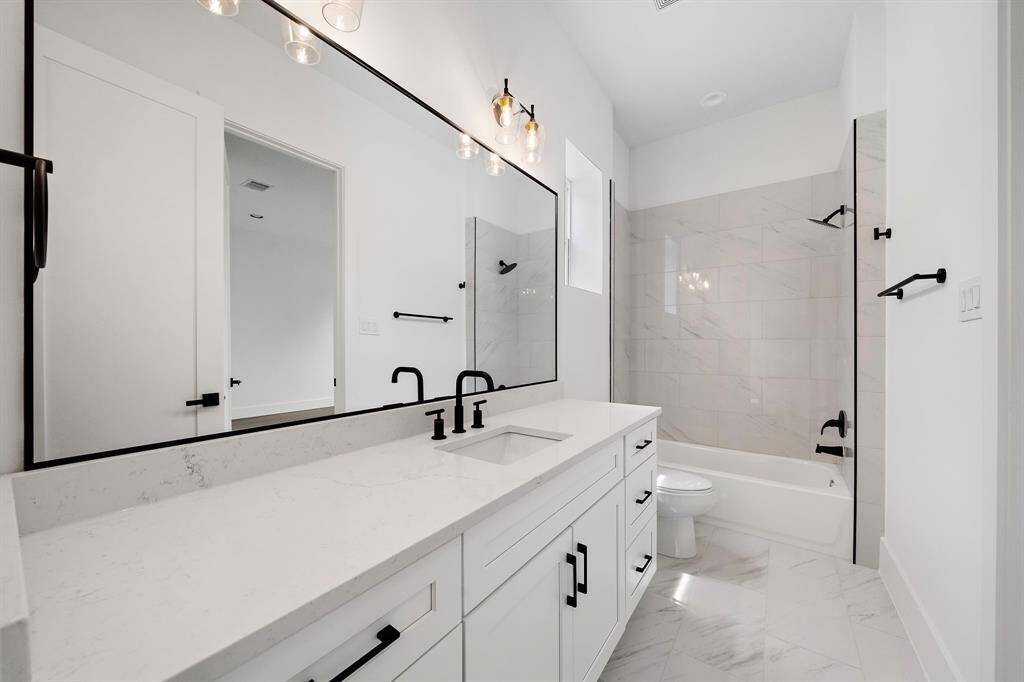 Guest bath with quartz counters, black matte hardware, and plenty of storage and counter space. (Photo is of a previously completed home.)