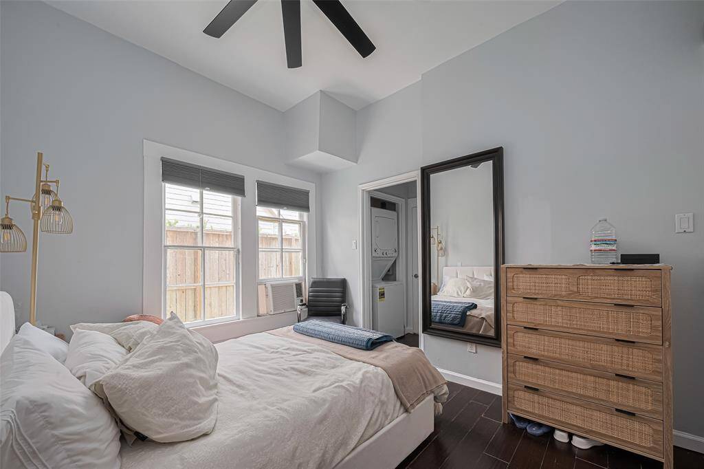 View of bedroom with hardwood flooring and high ceilings.