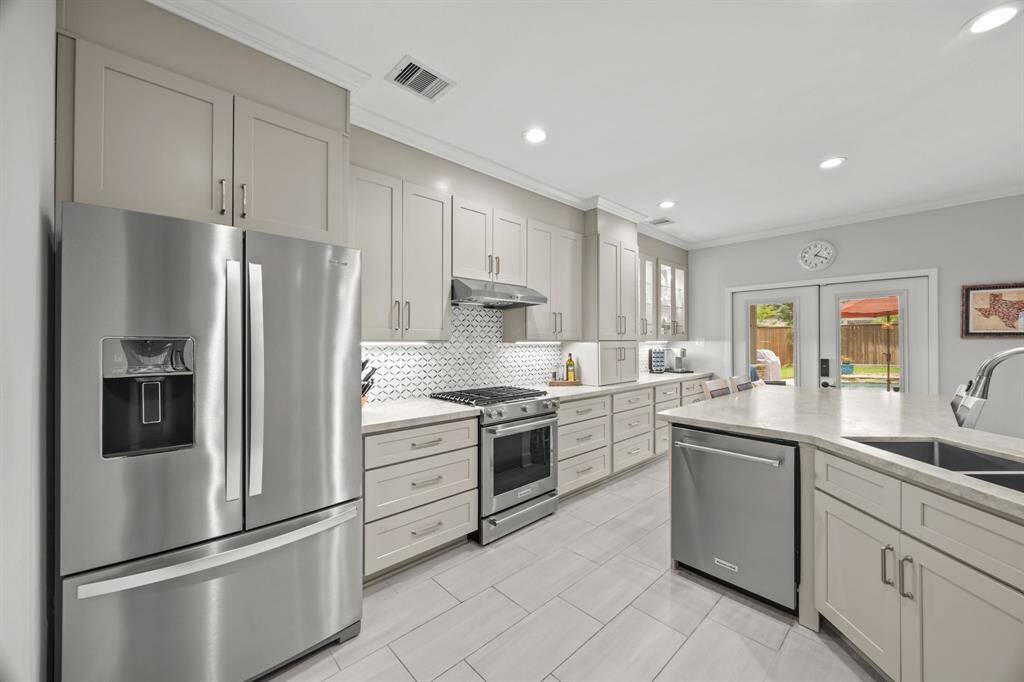 This kitchen features matte quartz countertops, modern appliances, and a striking tile backsplash—perfect for hosting gatherings.