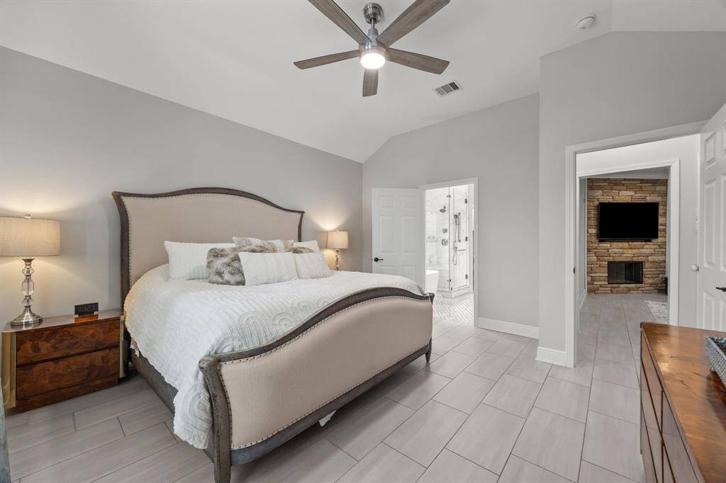 Elegant primary bedroom with sleek tile flooring and a luxurious en-suite bathroom.