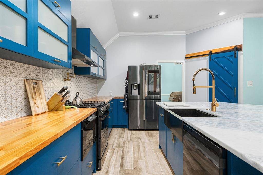 Cooking is a dream with top-tier stainless steel appliances, including a gas range and built-in microwave, while the deep single-bowl sink adds practicality. Crown molding throughout and modern recessed lighting.